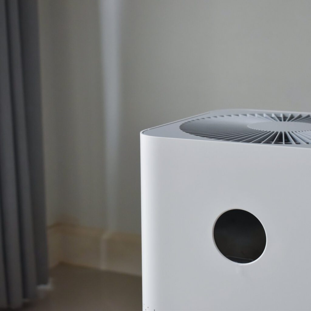 A white air conditioner sitting in the corner of a room.