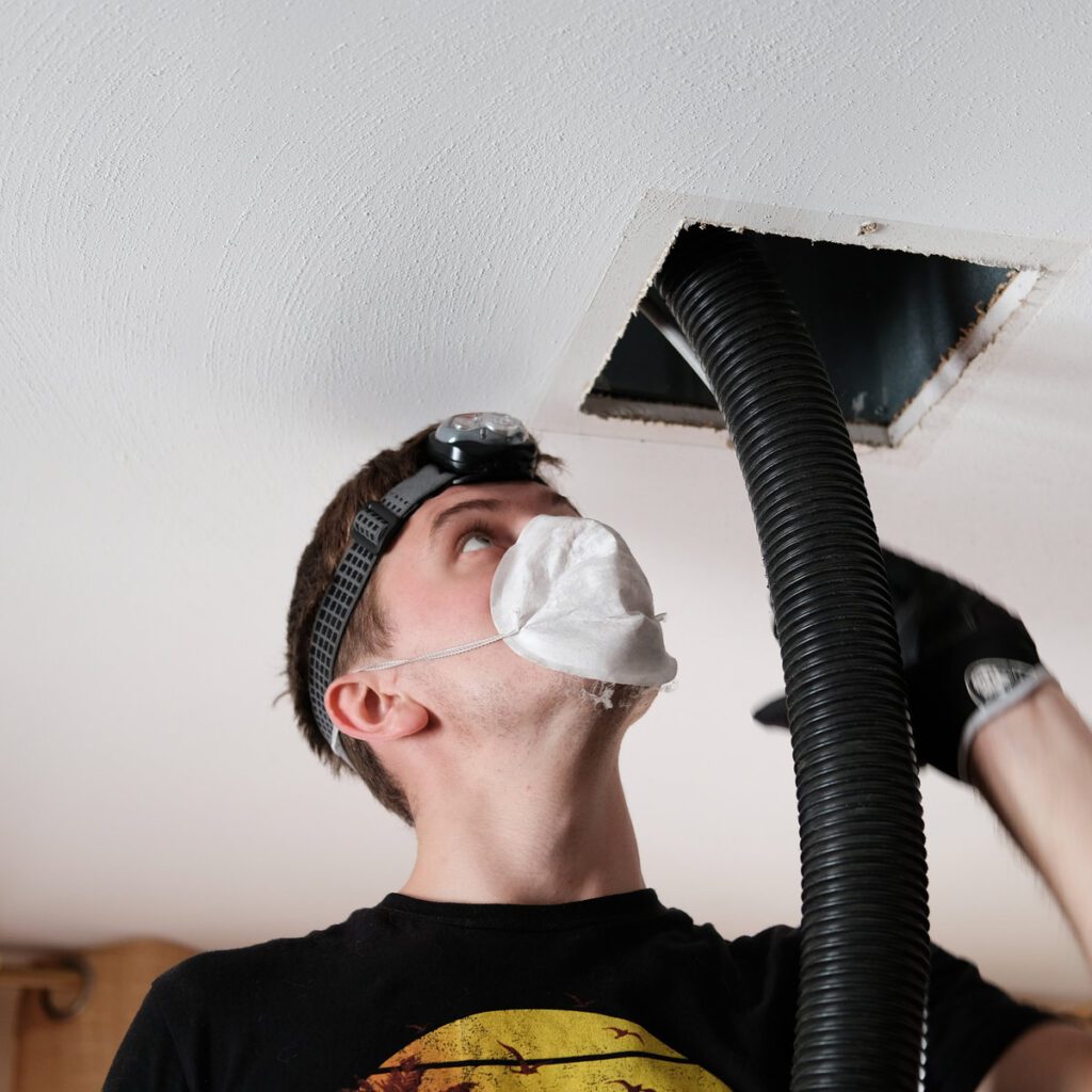 A man in black shirt holding up a duct.