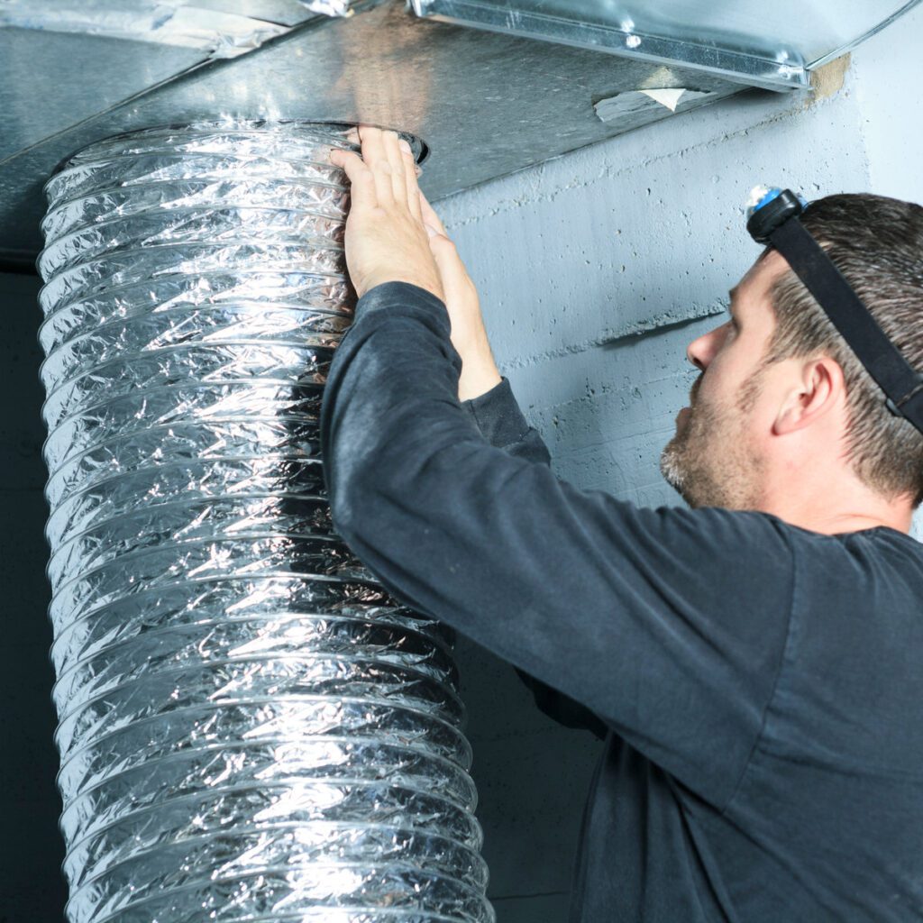 A man working on the inside of an air duct.