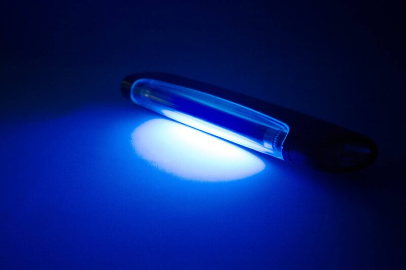 A blue light is shining on the tip of a pen.