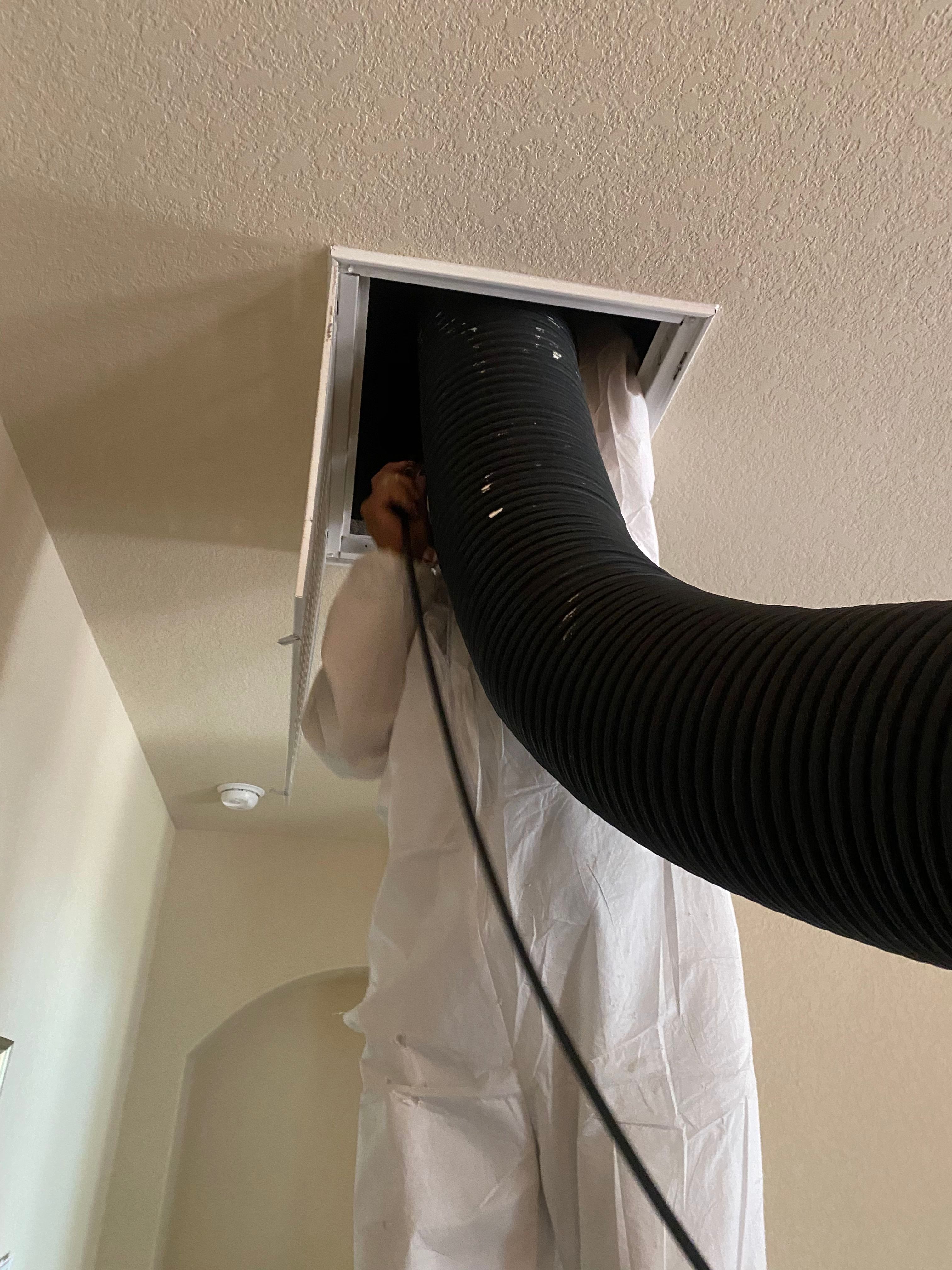 A person is holding the air duct hose to vent.