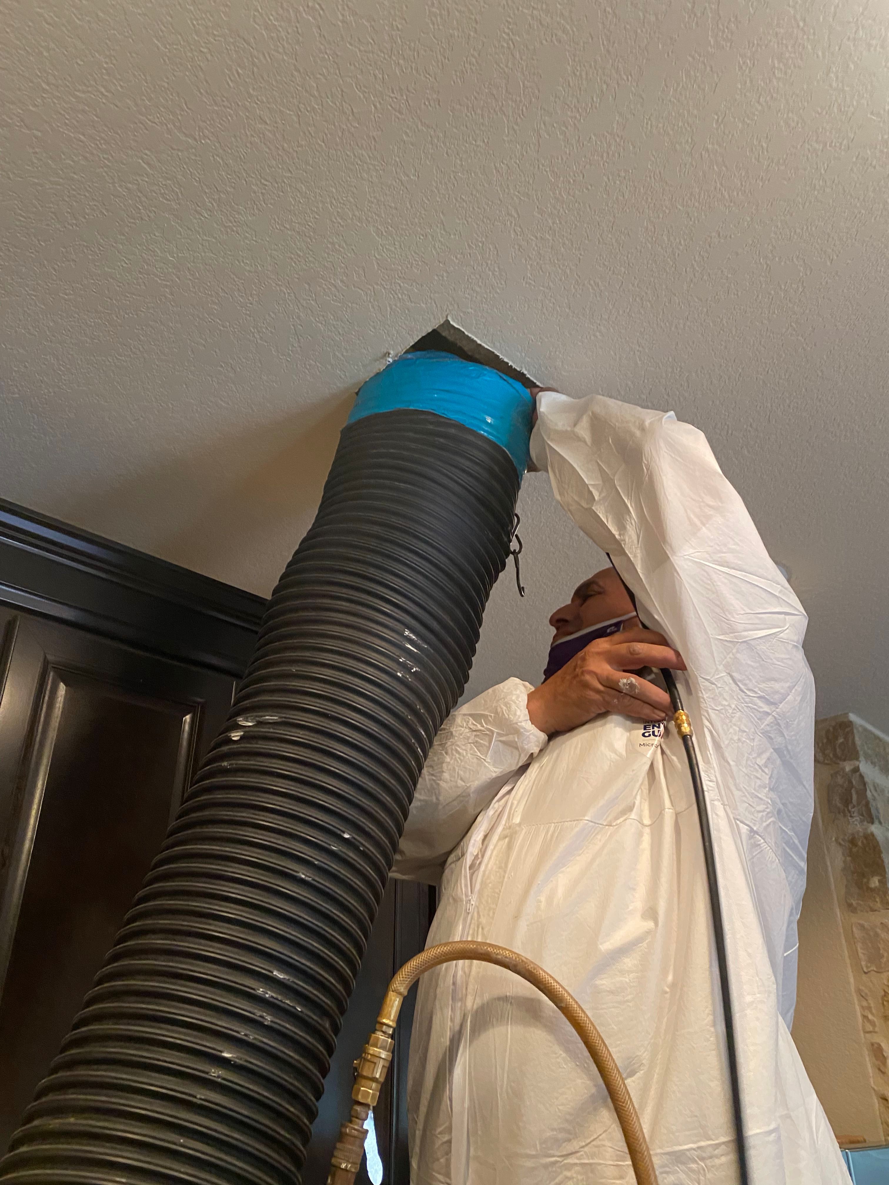 A man is holding on to the wall of an air vent